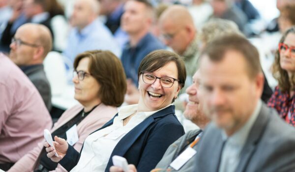 Group of diverse adults smiling and engaging during an indoor business meeting, showcasing teamwork.